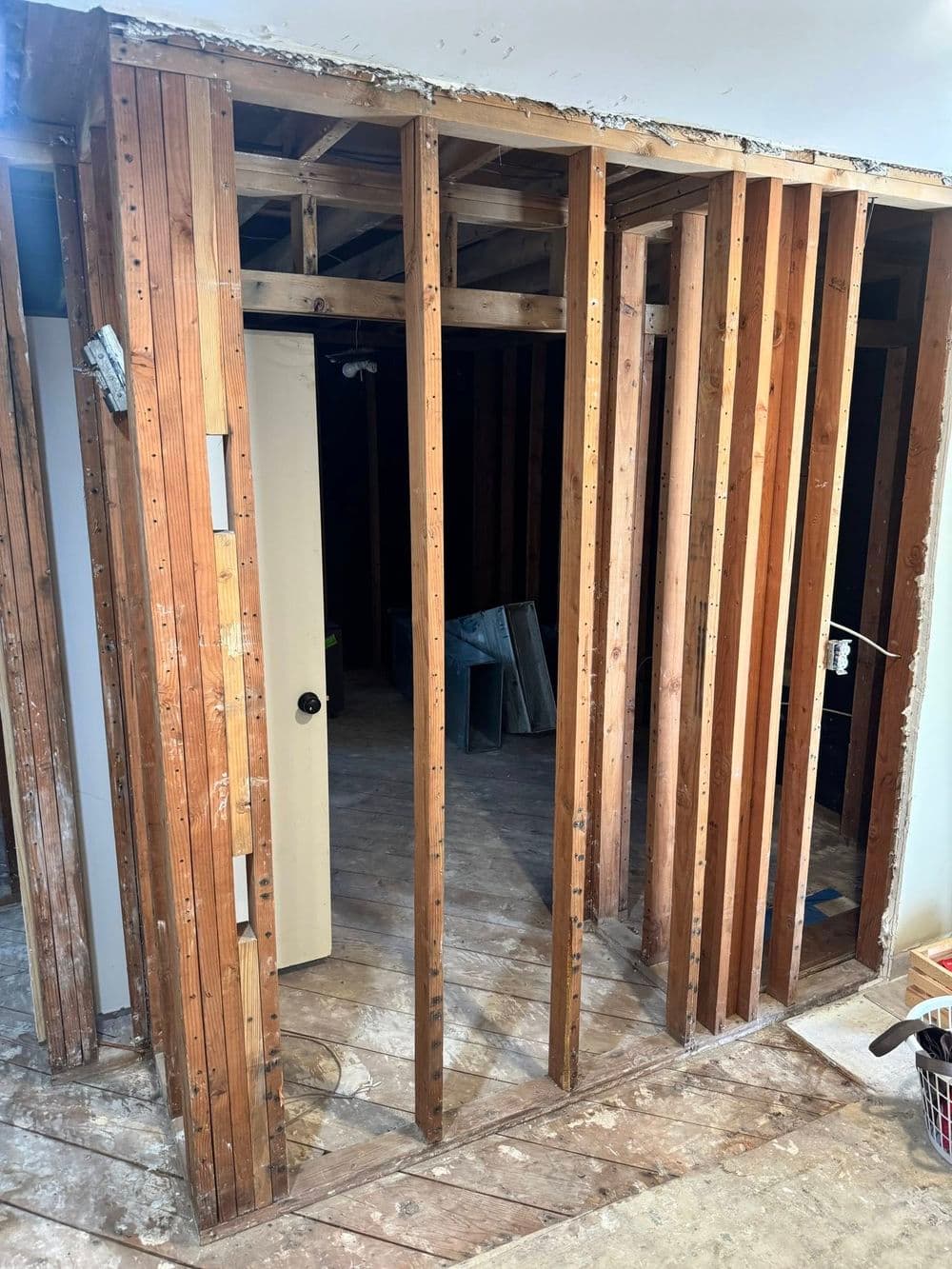 Exposed wooden framing of a room under renovation with flooring and walls visible.