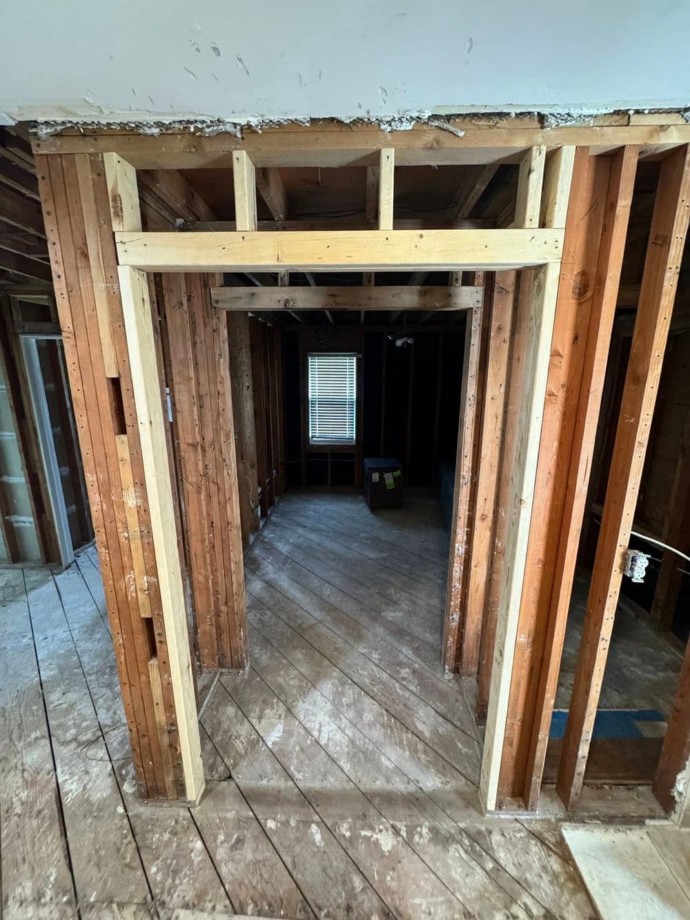 Interior construction showing framed doorway and exposed wooden beams in a renovation project.