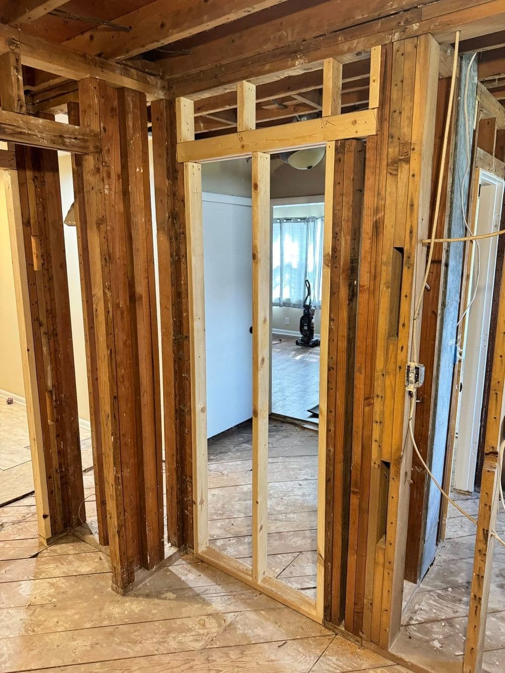 Exposed wooden framing in a home renovation showcasing a doorway under construction.