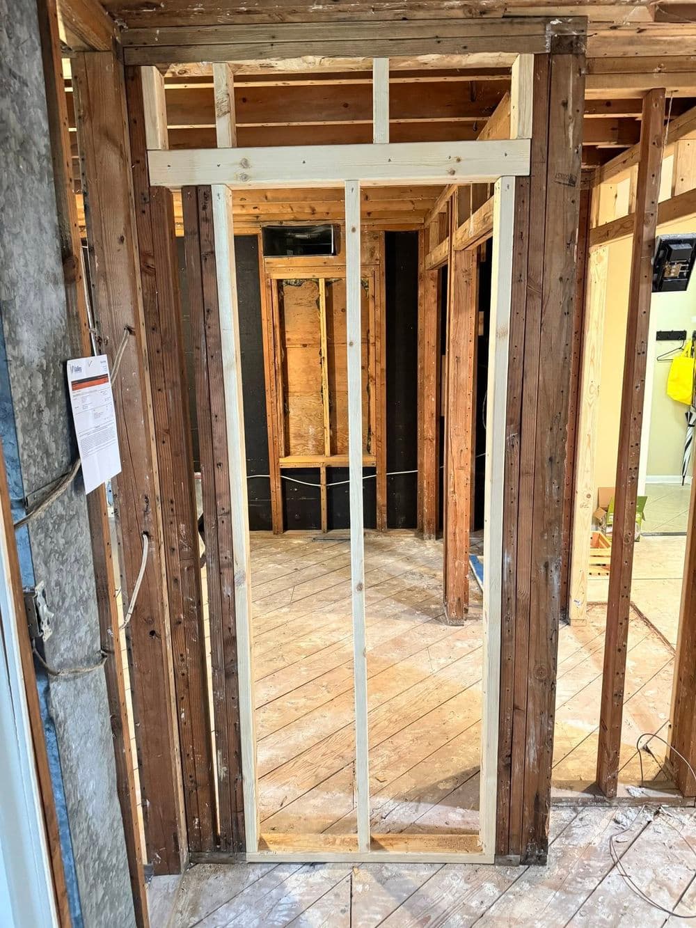 Framing for an interior door in a partially constructed room with exposed walls and floor.