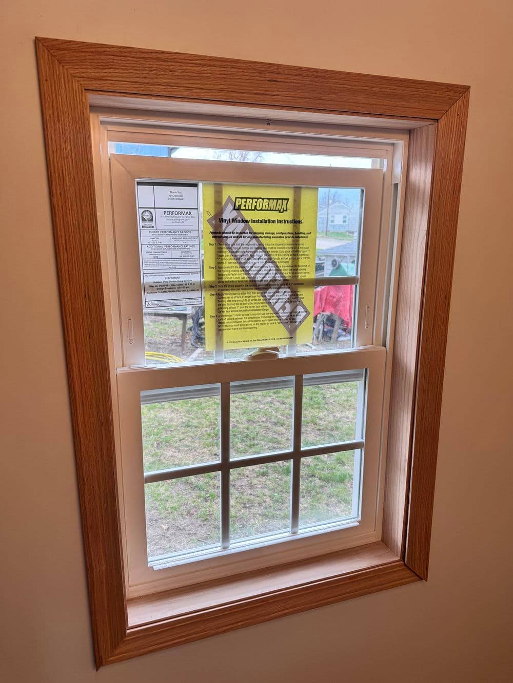 Window with informational poster about Performax insulation, framed in wood trim.