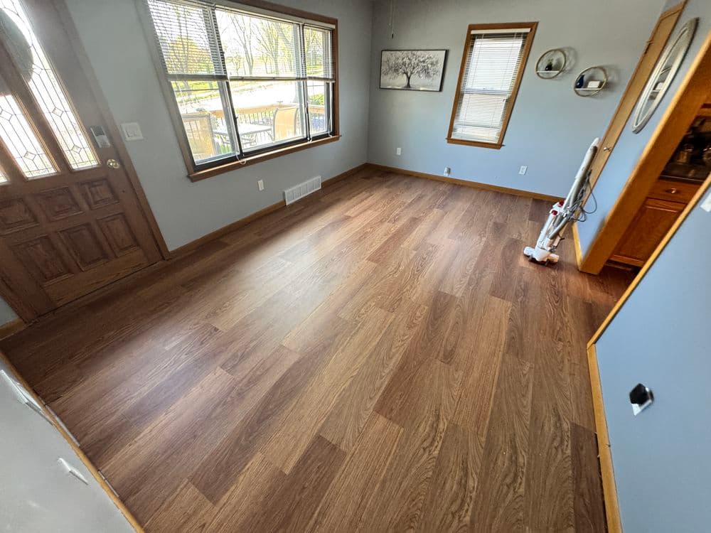 Empty room with new hardwood flooring, large windows, and a front door entrance.