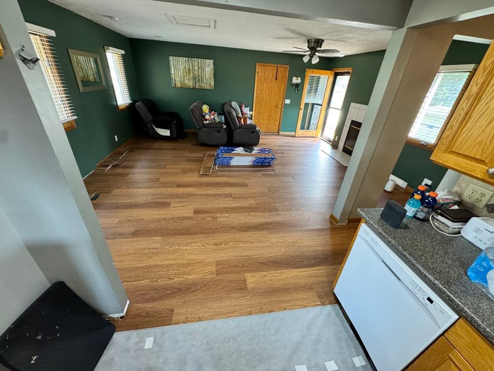 Spacious living room with dark green walls, hardwood flooring, and two recliners.