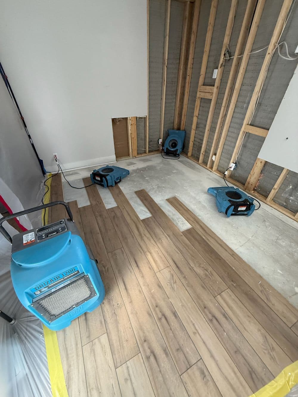 Drying equipment in a home renovation space with exposed walls and newly laid floor.
